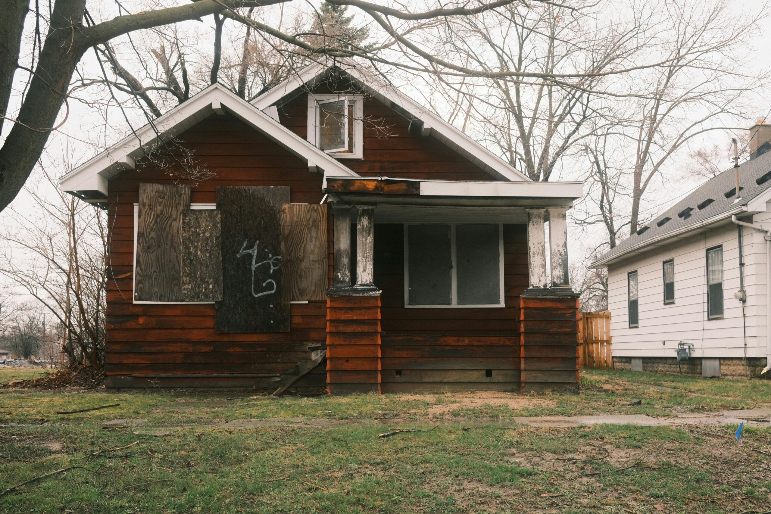 Abandoned brown wooden house with boarded windows.