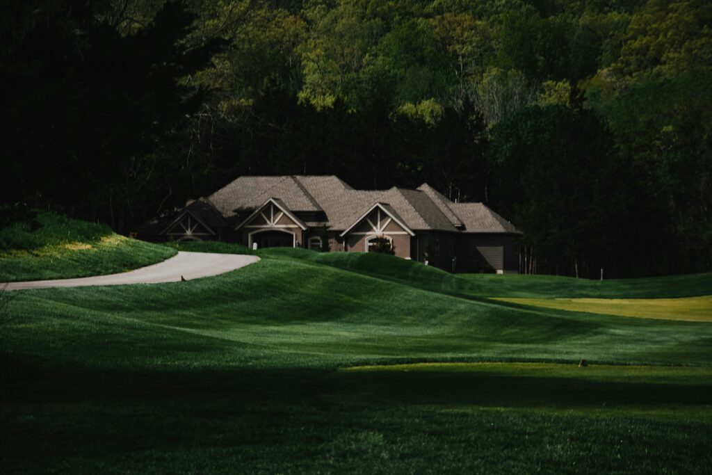 A view of a house in Missouri which has a field, road and trees.