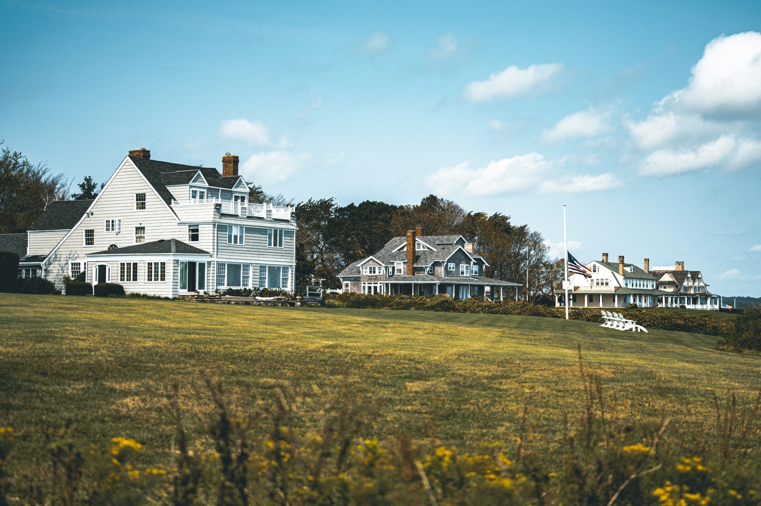 A landscape view of three houses in Rhode Island with the sky on the background.