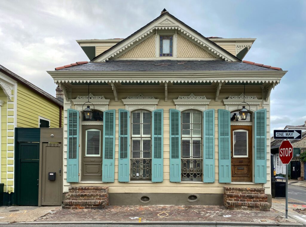 A front view of a house in Louisiana with a one way and stop sign on the right side of it.