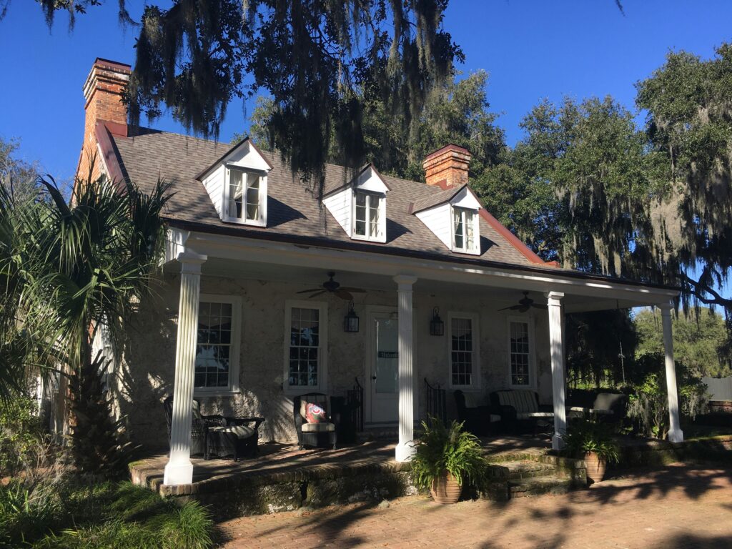 A house in South Carolina with 2 chimneys and trees beside it.