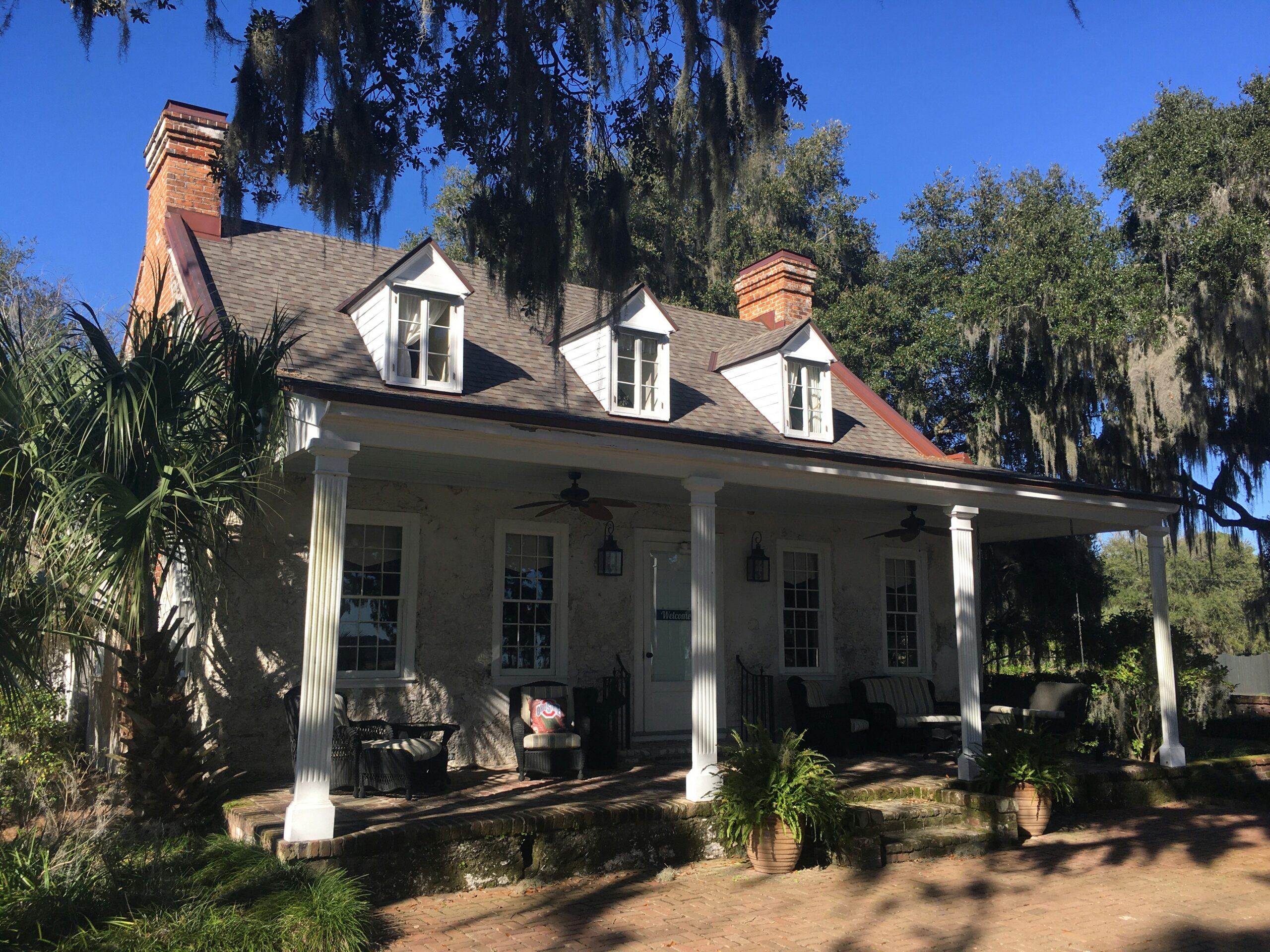 A house in South Carolina with 2 chimneys and trees beside it.