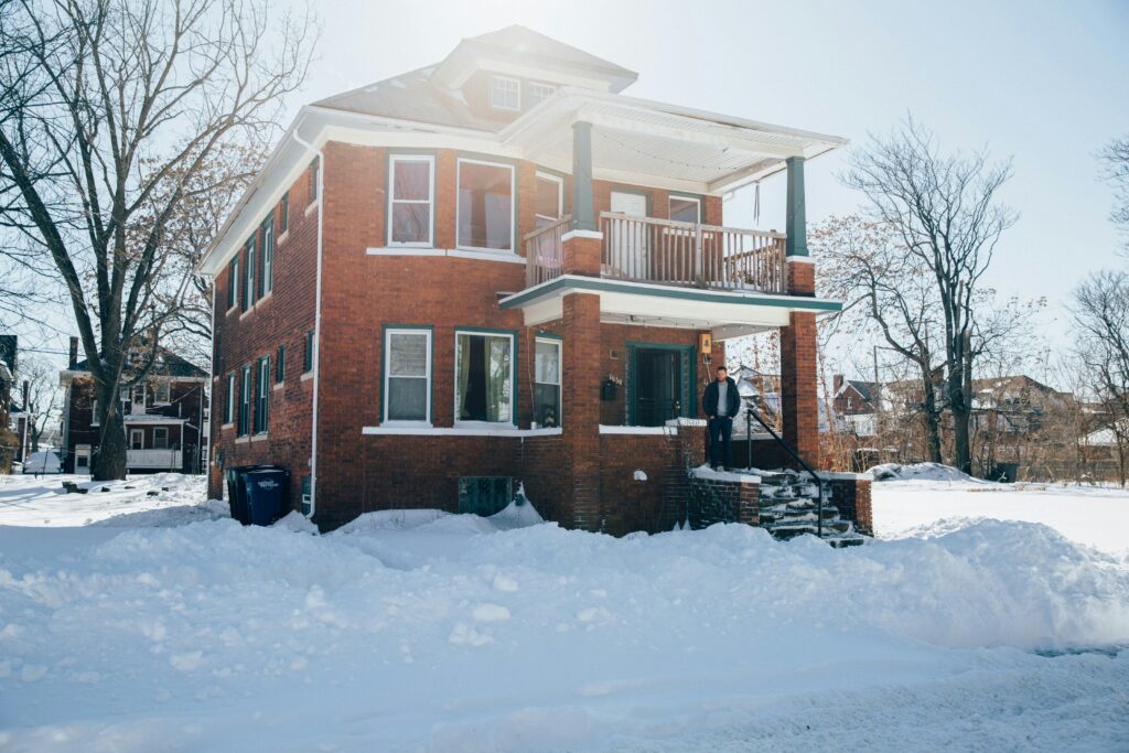 An eye level view of a house in Michigan with a man and snow.