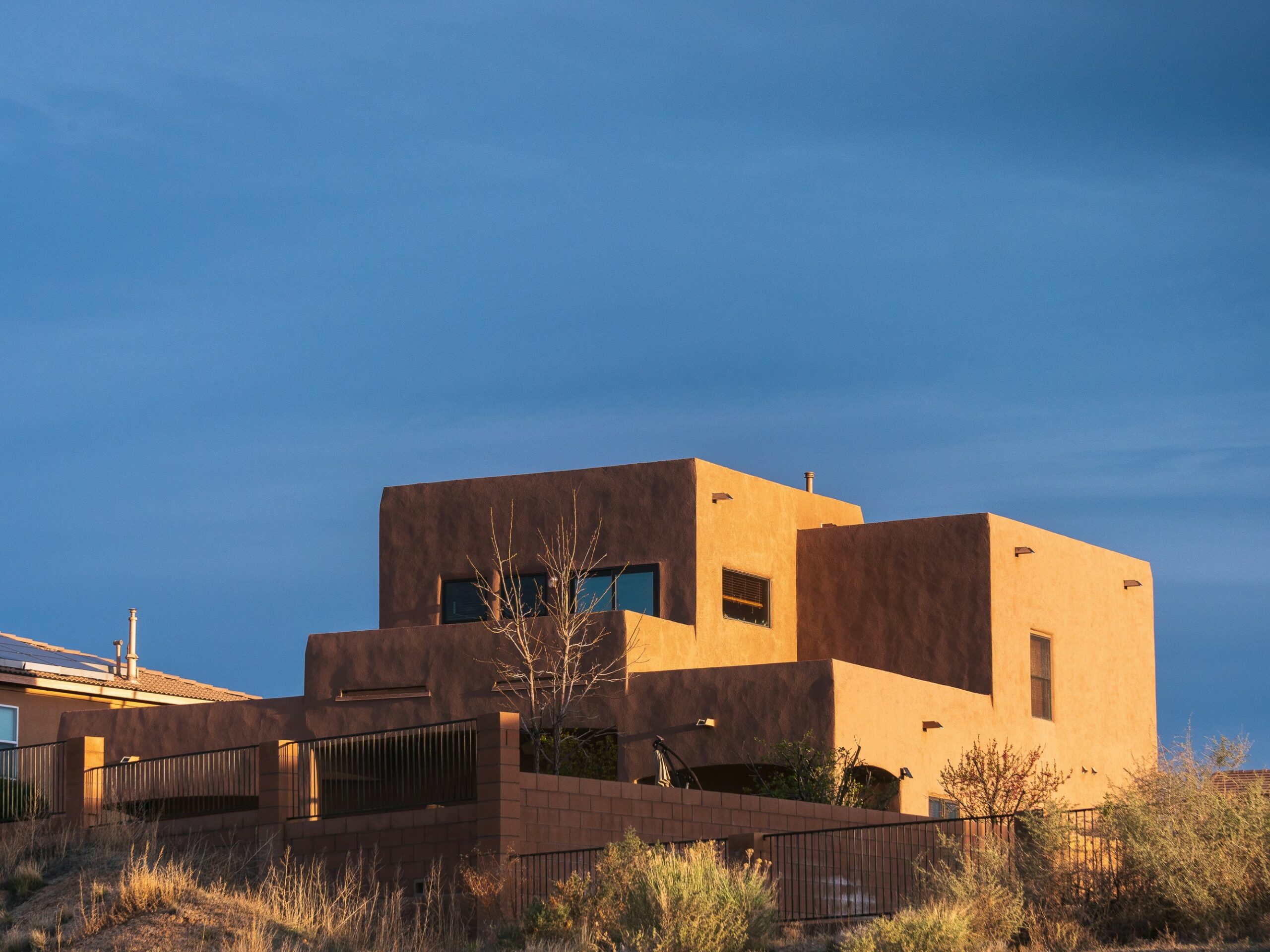A landscape view of a house in New Mexico with the sky at the top of the photo.