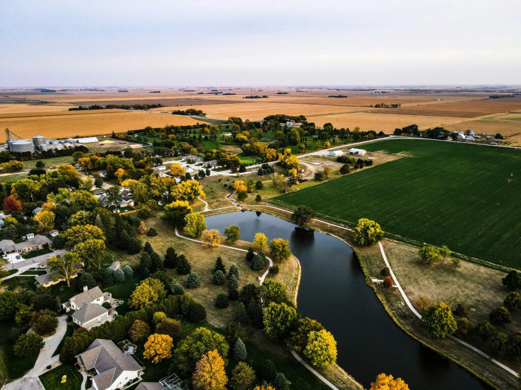A top view of houses in Nebraska with a pond and a field in it.