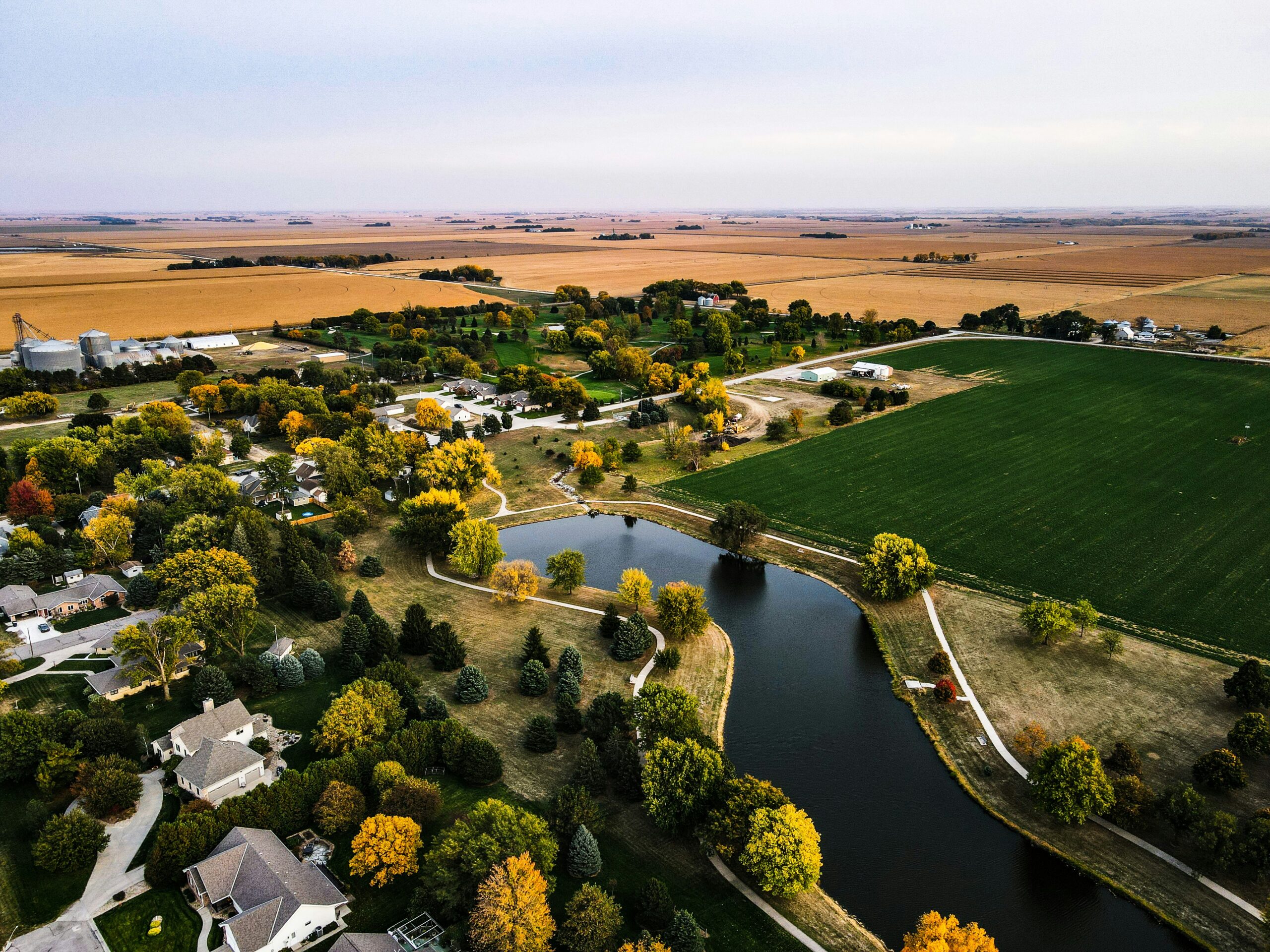 A top view of houses in Nebraska with a pond and a field in it.
