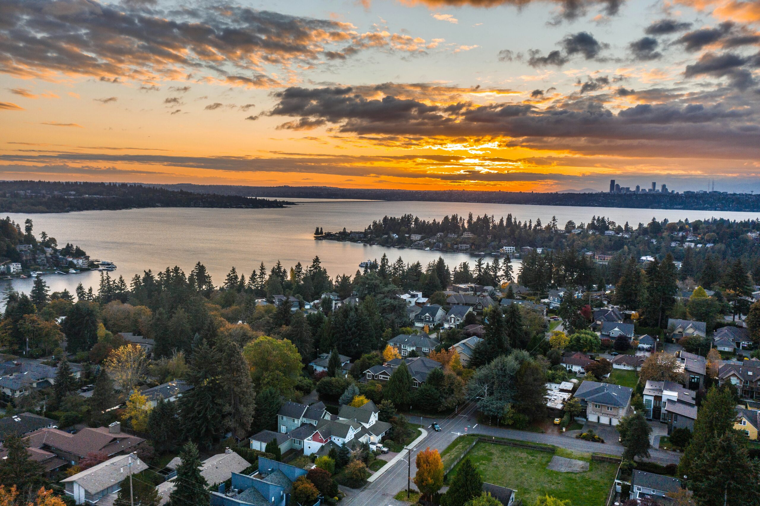 A top view of washington state, washington lake with houses and a sunset covered with clouds.